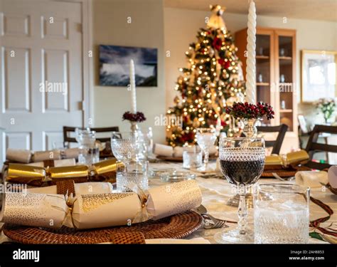 Traditional british christmas lunch table setting with crackers and glasses with xmas tree in ...