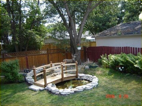 a wooden bridge over a small pond in a yard