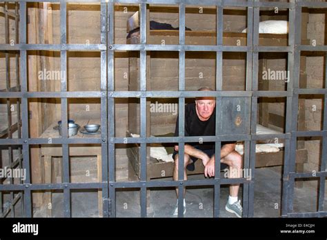 Man sitting on a cot in prison cell in old west jail Stock Photo - Alamy