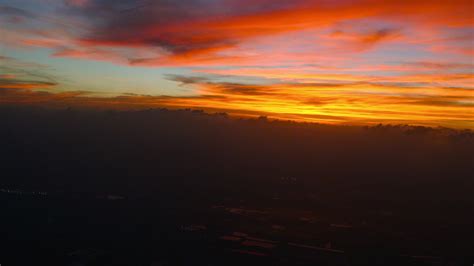 Fiery red sunset from an airplane window when landing. Wing view from ...