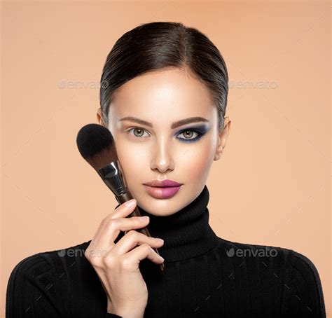 Portrait of a girl with cosmetic brush near face. Woman making makeup ...