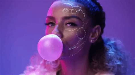 a woman with white face paint blowing a bubble into her mouth and holding a pink balloon in ...