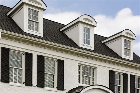 Close-up photograph of three dormer windows with an arched cap which contrasts with the angular ...