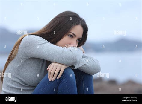 Sad girl looking away sitting alone on the beach Stock Photo - Alamy