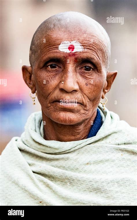 VARANASI - INDIA - 13 JANUARY 2018. Portrait of a sad and shaved old man walking on the ghat in ...