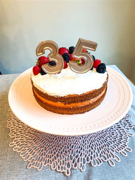 a white plate topped with a cake covered in frosting and fruit on top of it