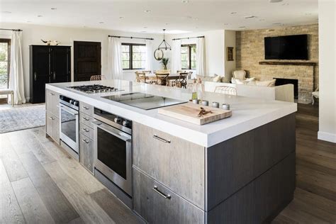 The gas and induction cooktop, along with the two ovens below, face the bar seating… | Modern ...