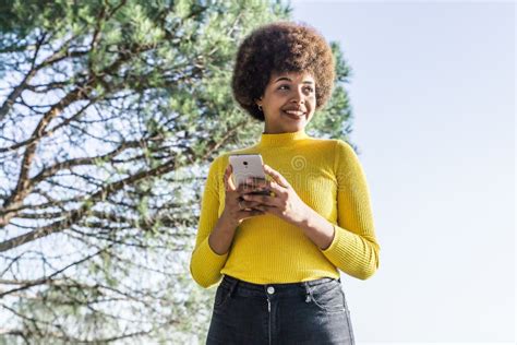 Beautiful Twenty Year Old Girl with Yellow Shirt Smiles with Her Mobile Phone in Her Hands Stock ...