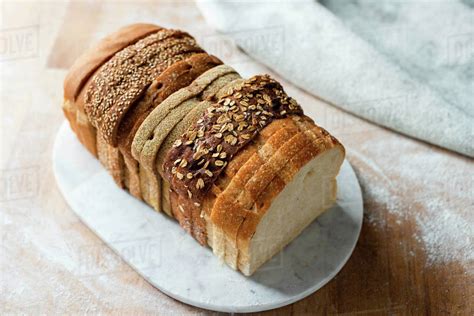 Sliced loaf made up of variety of white and wholemeal slices on cutting board, high angle view ...