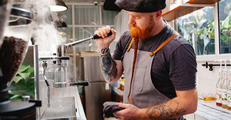 Tattooed barista cleaning coffee maker with steam · Free Stock Photo