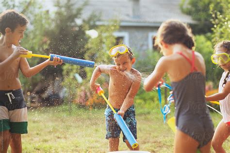 Children Playing With Water Guns In The Yard. by Dejan Ristovski