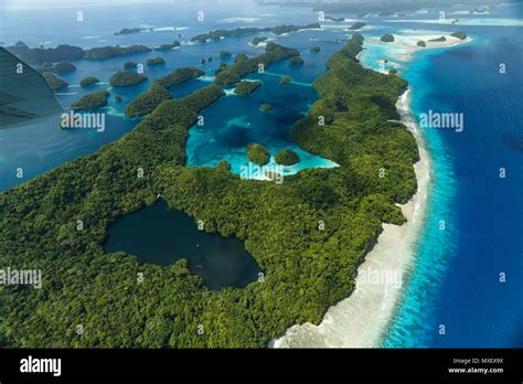 Aerial view of curious patterns of coral reefs, coral atolls, and vegetation on island with a ...