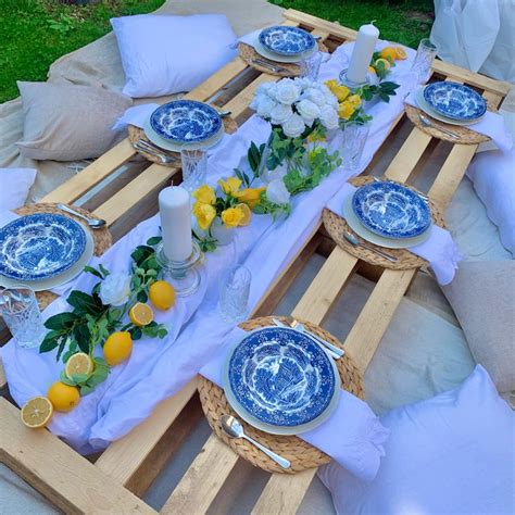 a table set with blue and white plates, lemons, flowers and candles on it