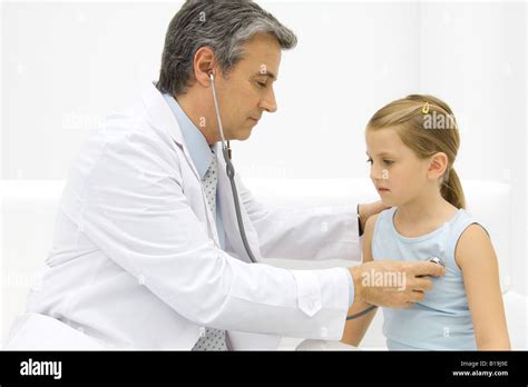 Doctor listening to little girl's heart with stethoscope, side view Stock Photo - Alamy