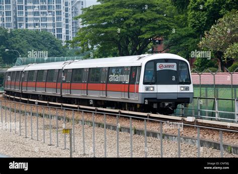 A metro train operated by SMRT approaches a station on an open section ...