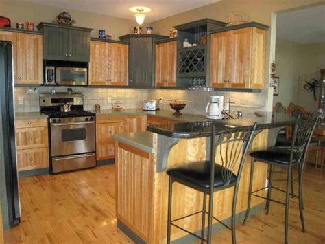 a kitchen with wooden floors and stainless steel appliances in the center, along with black bar ...