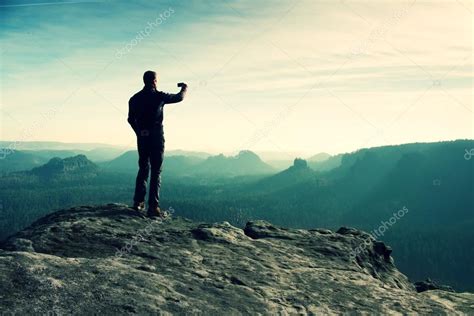 Tall hiker is taking photo by smart phone on the peak of mountain at ...