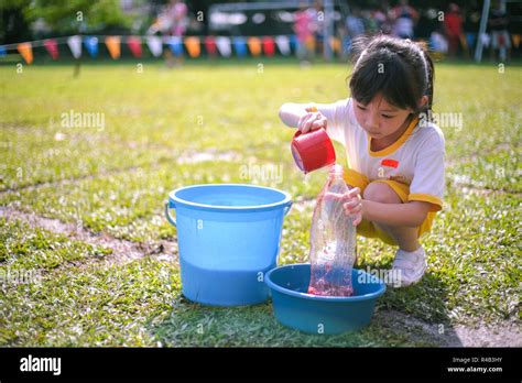 Children compete in fill-the-bottle game during their kindergarten ...