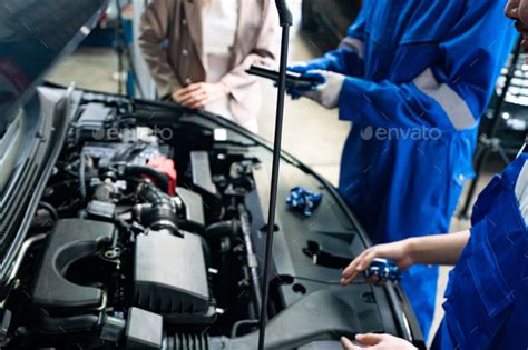 Mechanic in blue overalls checking serviceability of car engine Stock ...