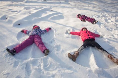 Premium Photo | Three children make snow angels in winter sunny day