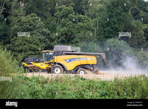 Side view of isolated UK combine harvester busy at work in the English countryside. Arable ...