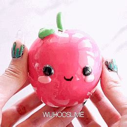 a hand holding a pink apple with black eyes