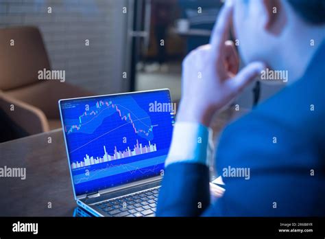 Stress businessman or stock market trader looks at laptop screen shows candlesticks chart ...