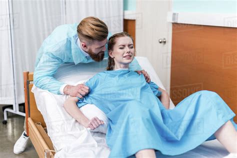 Pregnant woman giving birth in hospital while man hugging her - Stock Photo - Dissolve