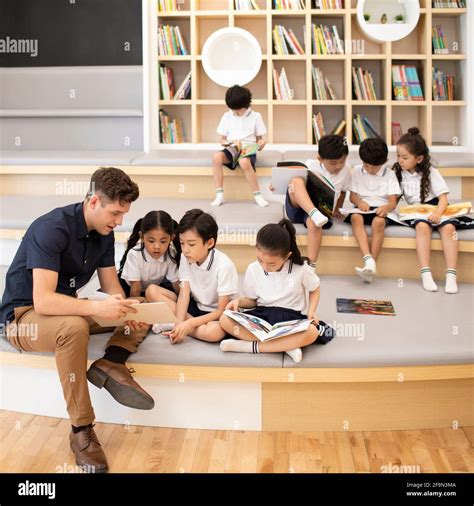 Children reading book in library Stock Photo - Alamy