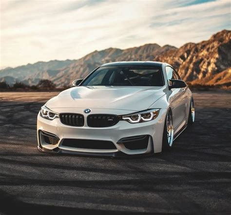 a white car parked on top of a parking lot next to some mountains in the background