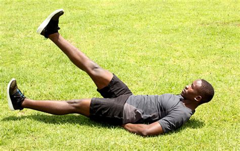 Healthy Man Lying on Grass Doing Ab Exercise Flutter Kicks