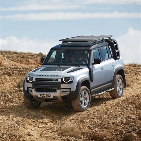 a silver and black four door suv driving down a dirt road on a hill side