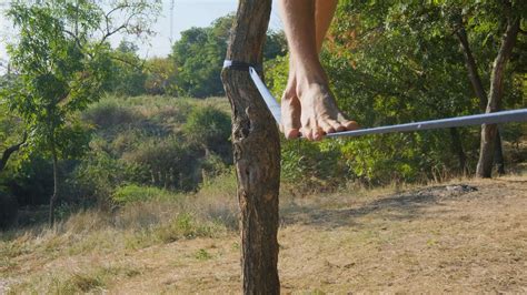 Athlete walking in slackline in the park with sea and blue sky on ...