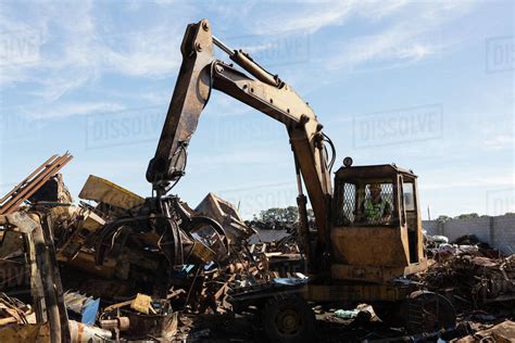 Crane lifting scrap metal in the junkyard - Stock Photo - Dissolve