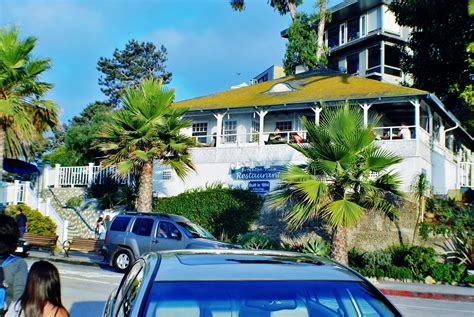 a blue car driving down a street next to a tall white building with palm trees