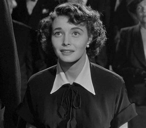 an old black and white photo of a woman in front of other people wearing suits