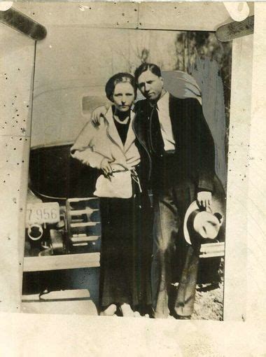 an old black and white photo of two people standing in front of a car ...