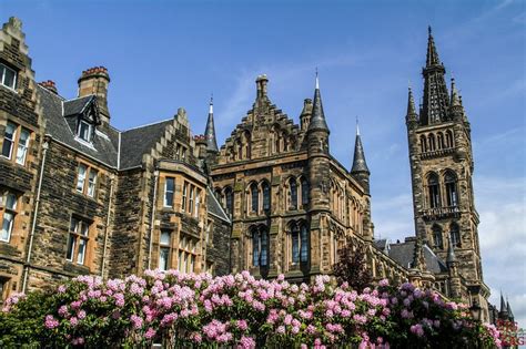 an old building with pink flowers in the foreground