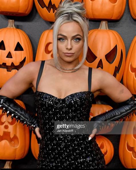 a woman in a black dress and leather gloves posing for the camera with ...