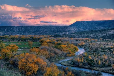 the sun is setting over a valley with trees and mountains in the ...