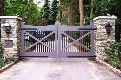 a driveway gate with stone pillars and gates