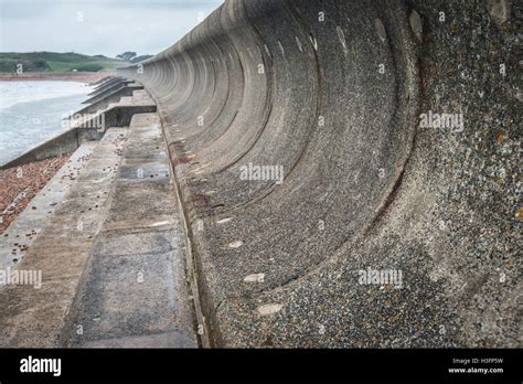 Curved sea wall which will reflect the energy of the waves back to the sea Stock Photo - Alamy