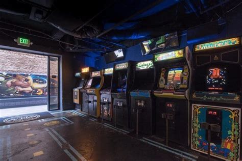 several arcade machines lined up against the wall in a room with blue lights and windows