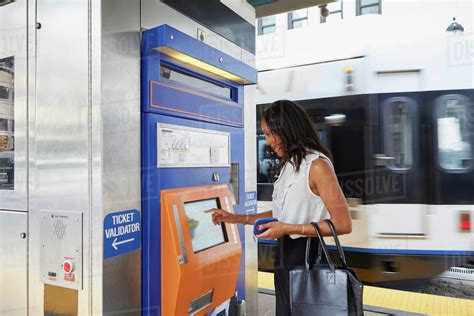 Businesswoman buying train ticket at machine - Stock Photo - Dissolve