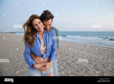 Man Hugging Woman from Behind at Beach Stock Photo - Alamy