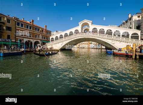 A gondola with passengers is crossing the Grand Canal, Canal Grande at Rialto Bridge, Ponte di ...