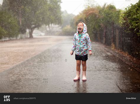 Girl sticking tongue out in the rain stock photo - OFFSET