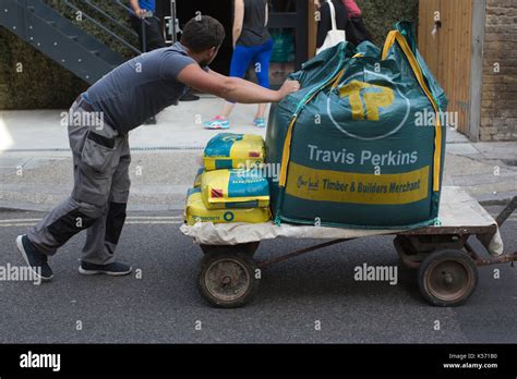 Man pushing trolley with Travis Perkins Timber & Builders Merchant ...