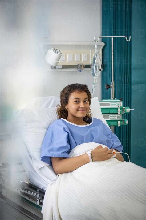 Portrait smiling girl patient in hospital bed stock photo