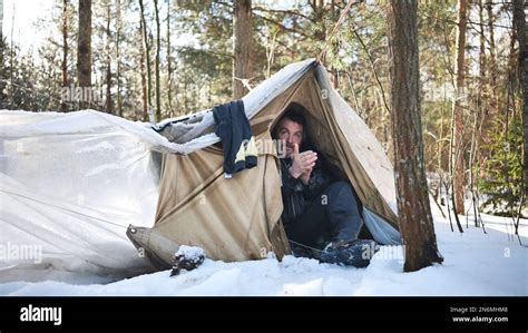 A homeless man climbs in and out of a tent in the woods in winter Stock ...